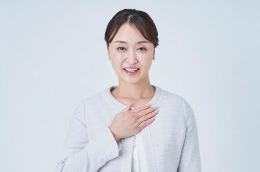 胸に手を当てるビジネスウーマン 胸に手を当てるビジネスウーマンの写真