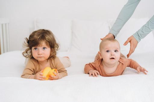 子供の横の赤ちゃんを支える手 赤ちゃん,かわいい,ベッドの写真素材