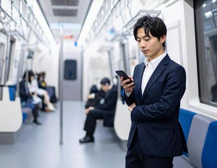 ビジネスシーン・地下鉄出張、スマホを見るの写真