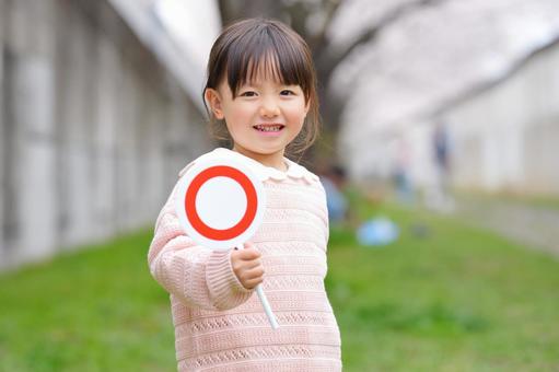 A girl holding a circle sign in front of cherry blossoms, JPG A girl holding a circle sign in front of cherry blossoms, JPG