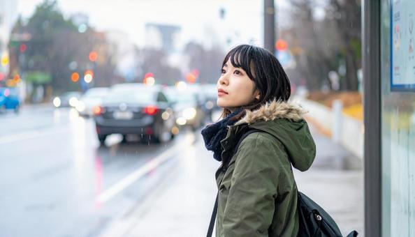 雨の中バス停でバスを待つ日本人女性 雨の中バス停でバスを待つ日本人女性の写真
