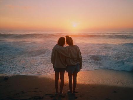 夕焼けのビーチで抱き合う二人の友人 夕焼けのビーチで抱き合う二人の友人の写真