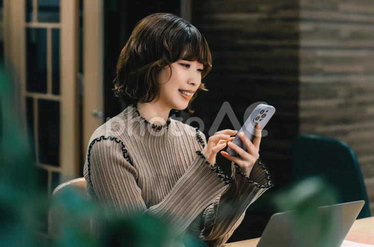 スマホを使う笑顔の女性・ビジネスウーマン 女性,スマホ,スマートフォンの写真素材