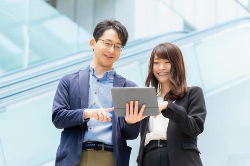 タブレットを見ながら話す男女ビジネスマン タブレットを見ながら話す男女ビジネスマン 男性,女性,男女の写真素材