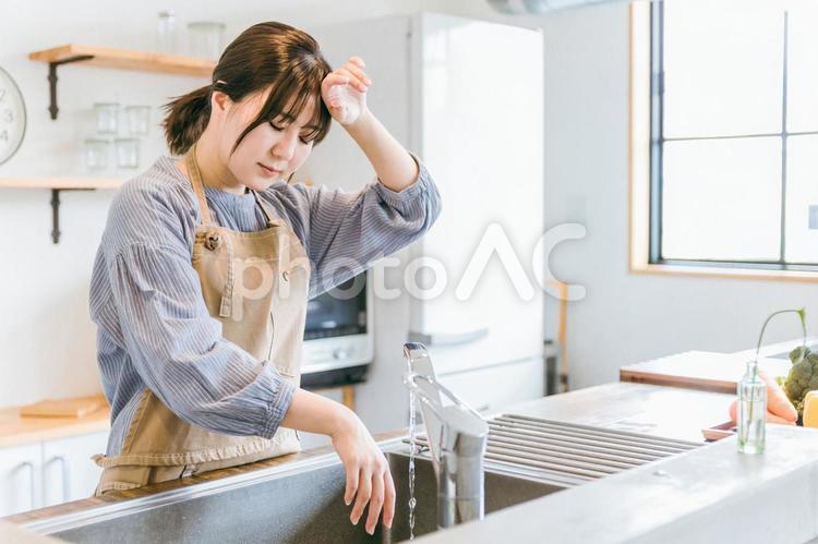 キッチンで後片付けをする女性（疲労） 女性,洗い物,後片付けの写真素材