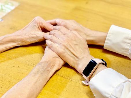 両手で高齢女性の手を上から握る女性の手 高齢者,介助,介護の写真素材