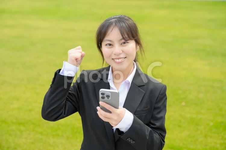 スマホを持ってガッツポーズをする女性 日本人,女性,20代の写真素材