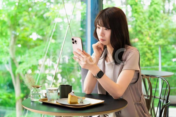 カフェでスマホを見ながら考える女性 女性,スマホ,スマートフォンの写真素材