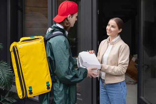ピザ配達の男性からピザを受け取る女性 配達,フードデリバリー,デリバリーの写真素材