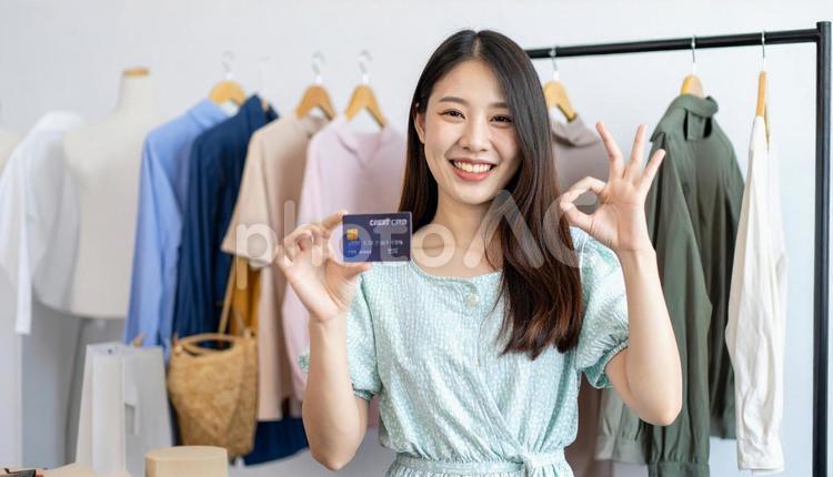 洋服を背景にカードを持ちOKサインの女性 キャッシュレス決済,クレジットカード,キャッシュレスの写真素材