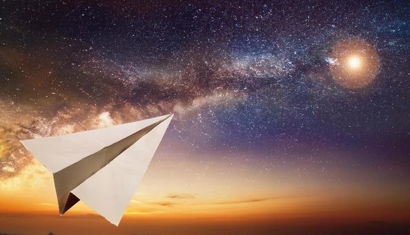 宇宙に向かって飛んでいる紙飛行機 宇宙に向かって飛んでいる紙飛行機の写真