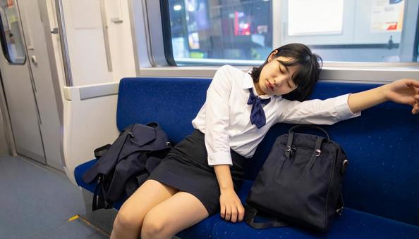 疲れて電車で熟睡している女子学生 疲れて電車で熟睡している女子学生の写真