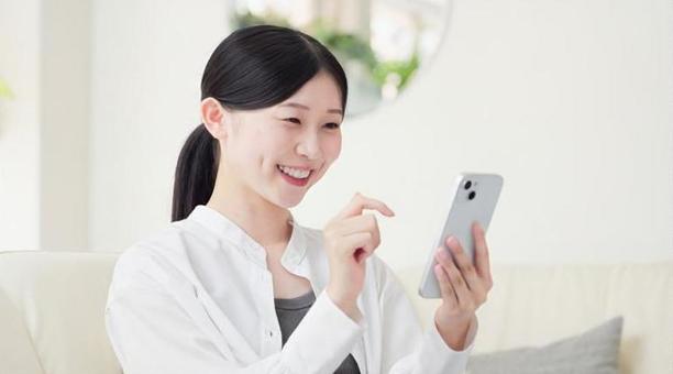 リビングでスマホを操作するアジア人女性 リビングでスマホを操作するアジア人女性 スマートフォン,操作,女性の写真素材