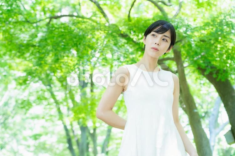 緑の中でスキンケアをする若い女性　 スキンケア,ビューティー,女性の写真素材