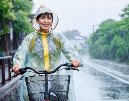 レインコートを着て自転車に乗る女性 レインコートを着て自転車に乗る女性の写真