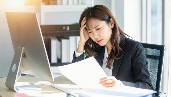 デスクで頭を抱えているビジネスマン デスクで頭を抱えているビジネスマンの写真