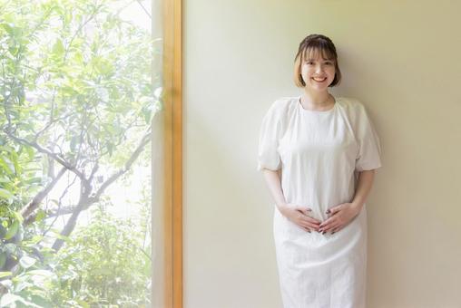 お腹を抑え壁にもたれる妊婦 お腹を抑え壁にもたれる妊婦 妊婦,妊娠,女性の写真素材