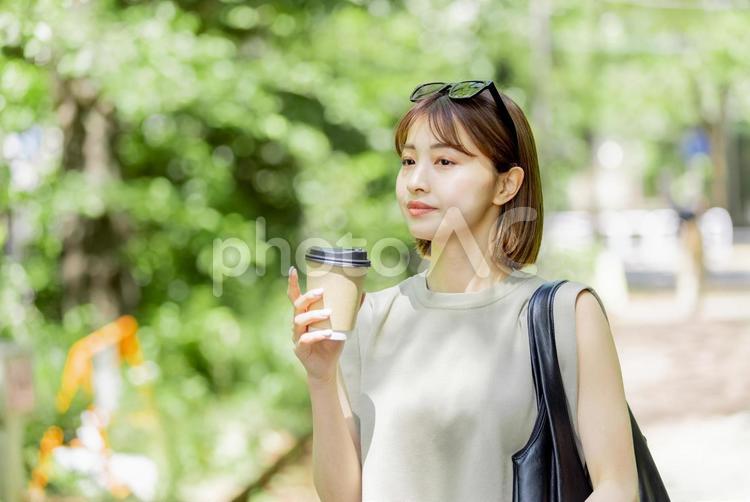 新緑の中コーヒーを飲む若い女性 女性,外出,お出かけの写真素材