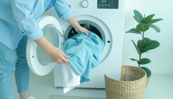洗濯機から洗濯物を取り出す女性の手 洗濯機から洗濯物を取り出す女性の手の写真