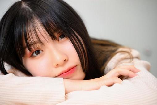 テーブルに伏せてこちらを見る10代の女性 テーブルに伏せてこちらを見る10代の女性の写真