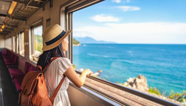 車窓から夏の海を見つめる日本人女性乗客 車窓から夏の海を見つめる日本人女性乗客の写真