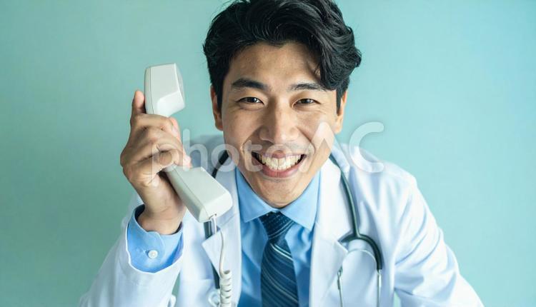 笑顔で固定電話をかける医師 電話診療,若い,電話機の写真素材