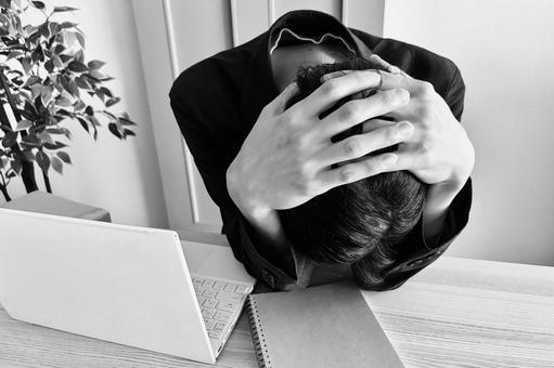 デスクで頭を抱える男性(モノクロ) デスクで頭を抱える男性(モノクロ) どうしよう,ショック,悩むの写真素材