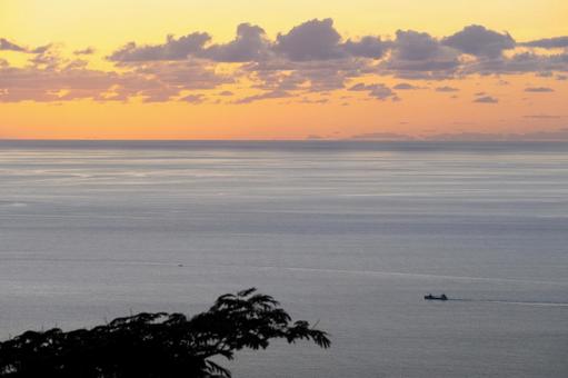 穏やかな海に浮かぶ船と夕暮れの空 穏やかな海に浮かぶ船と夕暮れの空の写真