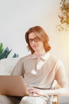 座って膝の上でノートパソコンを微笑む長髪の男性 男性,外国人,欧米人の写真素材