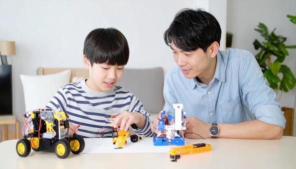 父親と一緒にプラモデルを作る男の子 父親と一緒にプラモデルを作る男の子の写真