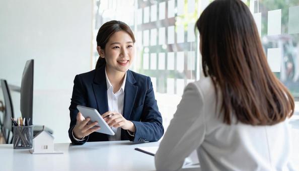 対面で客に説明する笑顔の日本人の働く女性 対面で客に説明する笑顔の日本人の働く女性の写真