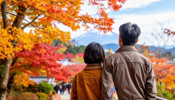 美しい紅葉を眺める夫婦の後ろ姿の写真