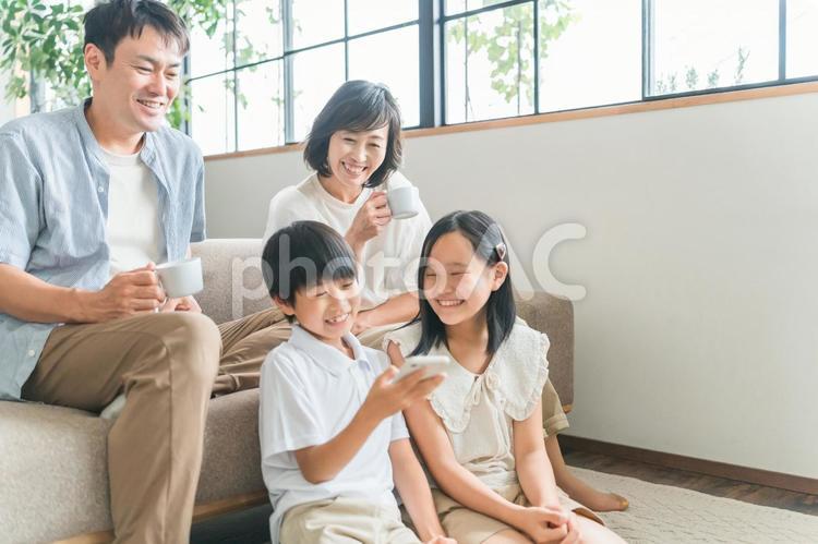 リビングでスマホを見る笑顔の家族 ファミリー,家族,スマホの写真素材