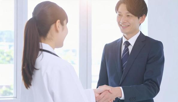 握手するビジネスパーソンと医者 握手するビジネスパーソンと医者の写真