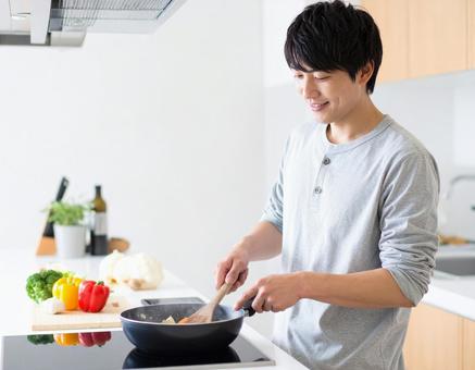 キッチンで料理をする男性 キッチンで料理をする男性の写真