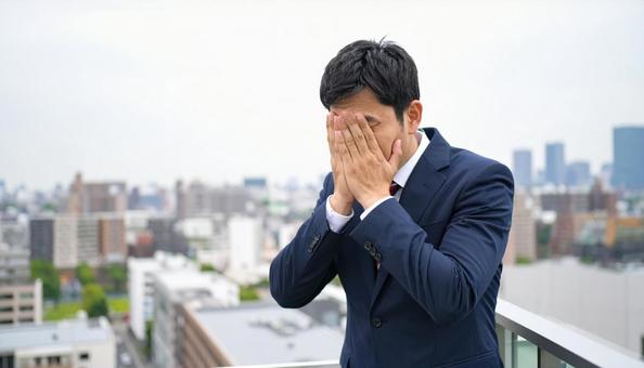 オフィスビルの屋上で苦悩するビジネスマン オフィスビルの屋上で苦悩するビジネスマンの写真