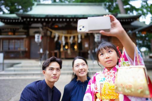 神社の前でスマホで自撮りをする家族 神社の前でスマホで自撮りをする家族 七五三,お参り,七五三参りの写真素材