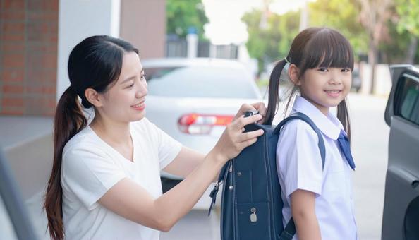 子供のランドセルに防犯ブザーを付ける母親 子供のランドセルに防犯ブザーを付ける母親の写真