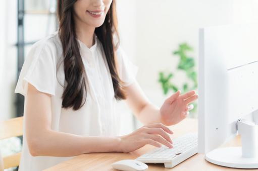 リビングでテレワークをする若い女性 リビングでテレワークをする若い女性の写真