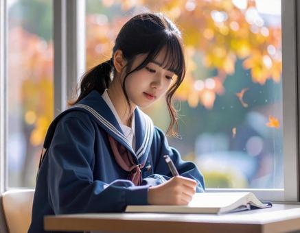 秋の教室で勉強に集中する女子学生の写真