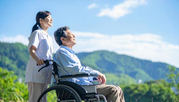 青空を見つめる車いすシニアと介護の女性 青空を見つめる車いすシニアと介護の女性の写真