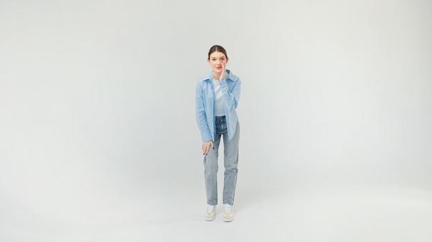 口元に手を当て話す青いシャツの女性 口元に手を当て話す青いシャツの女性の写真