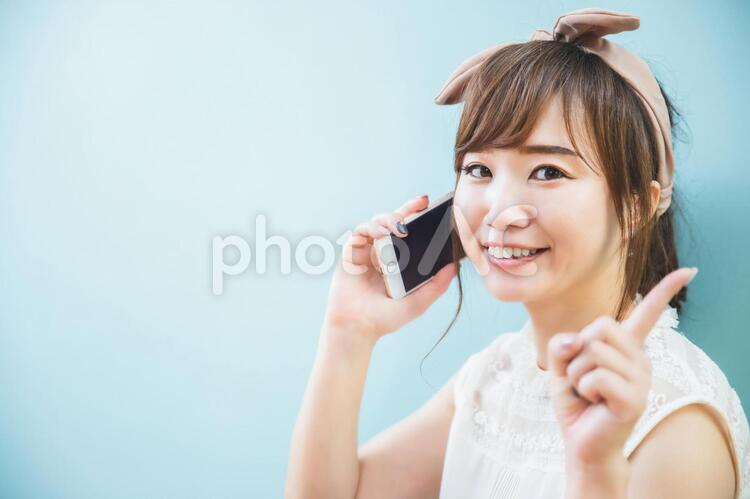 スマホで通話しながら指差しをする女性 スマホ,電話,スマートフォンの写真素材
