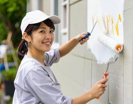DIYで外壁塗装する女性 DIYで外壁塗装する女性の写真