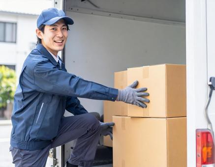 トラックから荷物を出す宅配男性ドライバー トラックから荷物を出す宅配男性ドライバーの写真