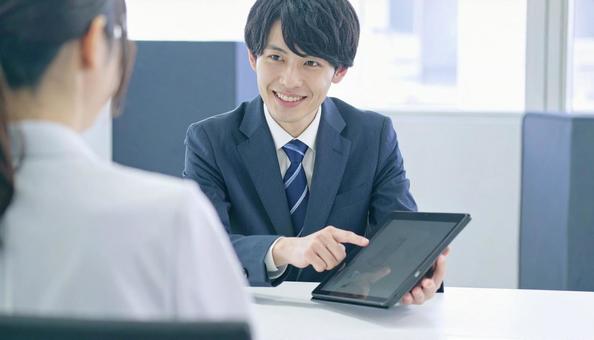 タブレットを使って説明する男性営業マン タブレットを使って説明する男性営業マンの写真