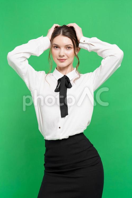 両手で頭を押さえカメラ目線の女性（緑背景） 女性,立つ,ポーズの写真素材