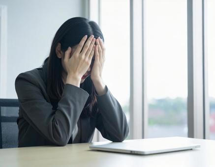 オフィスのデスクで泣いている女性会社員 オフィスのデスクで泣いている女性会社員の写真