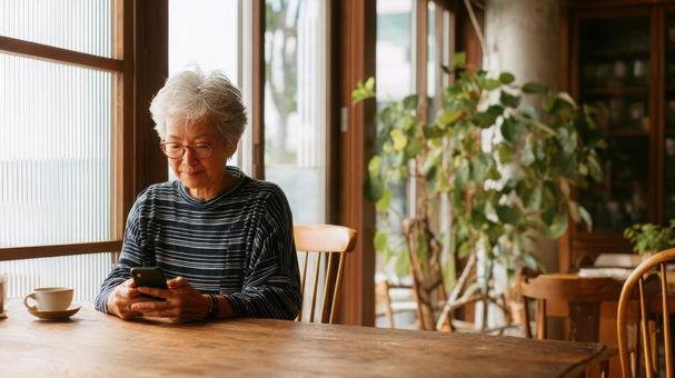 Senior woman in a cafe operating a smartphone and smiling, senior, senior citizens, female, JPG