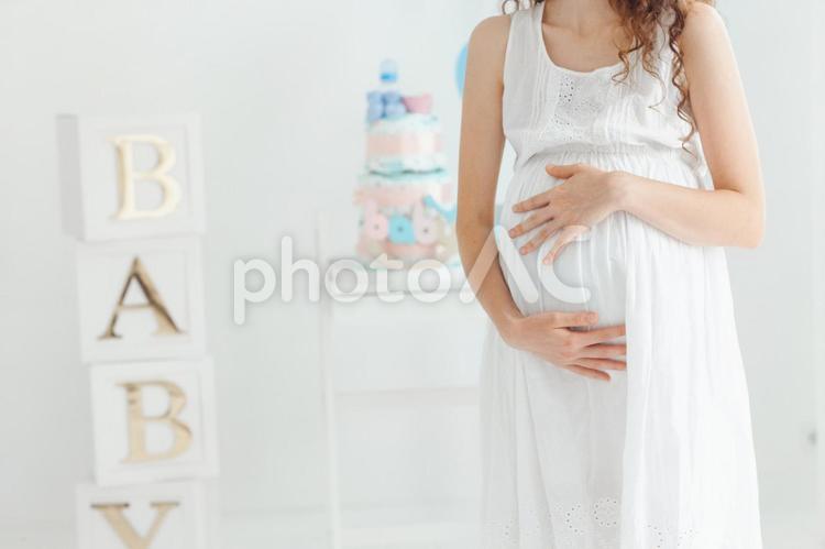 お腹を触って正面を向いた妊婦さんの手元 手元,女性,人物の写真素材